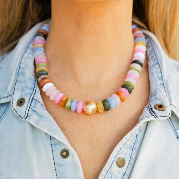 Woman wearing a multicolored stoned gem necklace with a gold ball in the middle