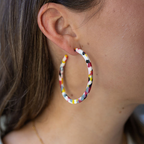 Model wearing large white and multicolored resin hoop earring 