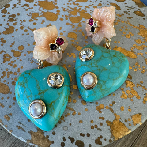 Blue gemstone dangle earrings with cream colored flowers attached to them