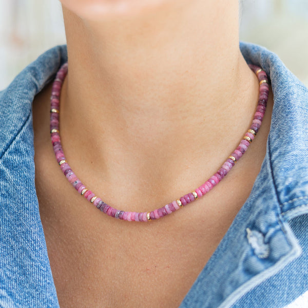 Woman wearing a purple/pink beaded small necklace/choker around her neck