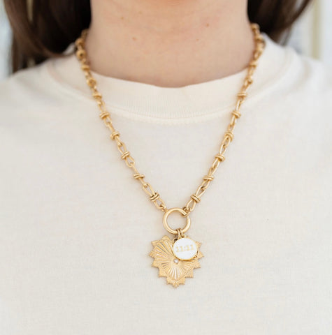 Picture of model wearing a gold toggle chain with a large gold heart pendant with a diamond at its center and a white 11:11 charm.