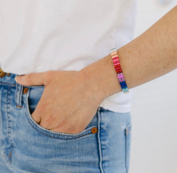 Woman wearing bright multi-colored beaded stretchy bracelet.