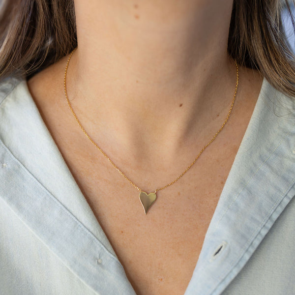 Model wearing dainty gold chain with gold heart pendant