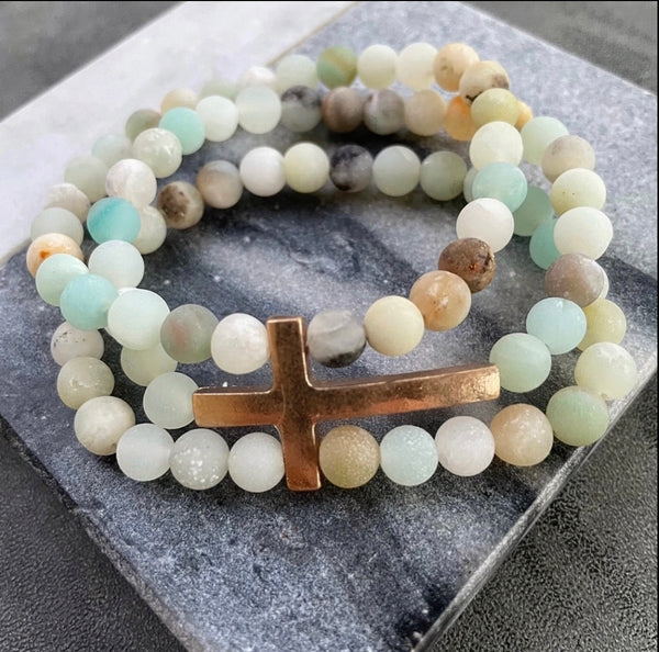 A multicolored gemstone bracelet stack with a gold cross 