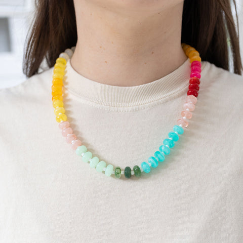 Model wearing brightly colored beaded necklace of yellow, white, blue, green and pinks.