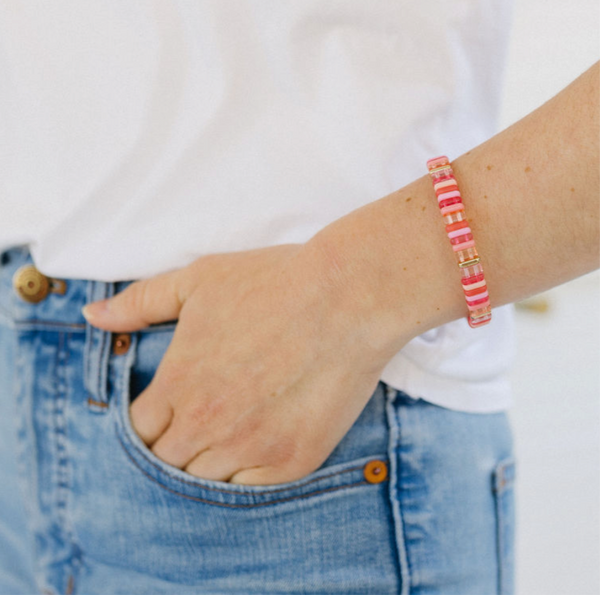 Picture of a woman's wrist displaying a coral, pink and white beaded bracelet.