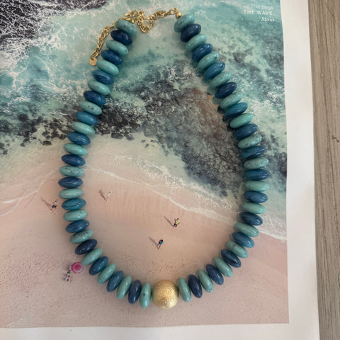 A resin and gold necklace with shades of blue