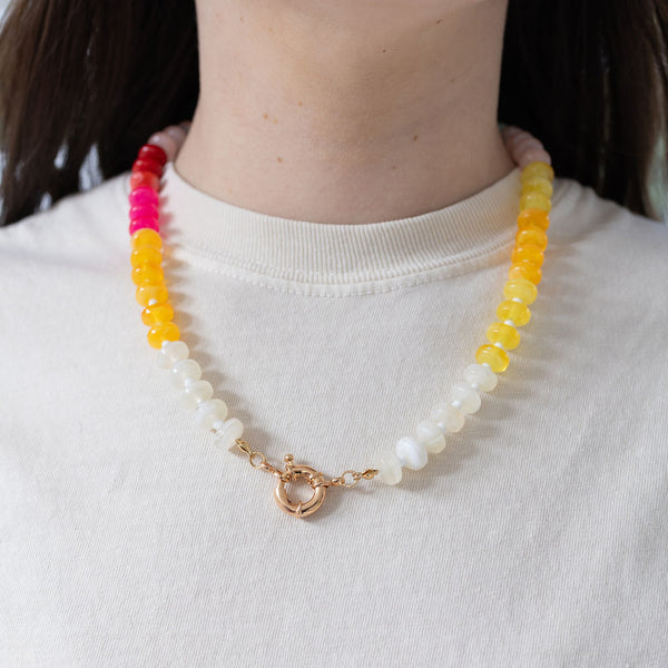 Model wearing a brightly colored beaded necklace of white, yellow and pinks.