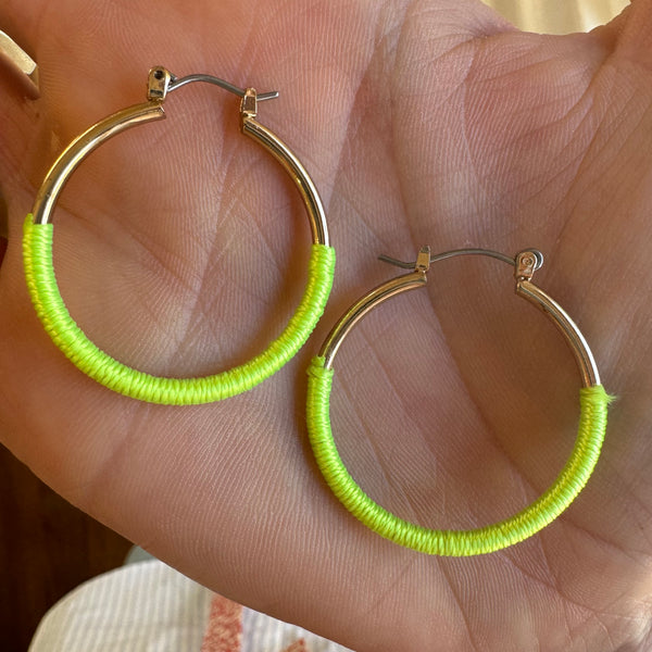 Person holding gold and neon wrapped hoops