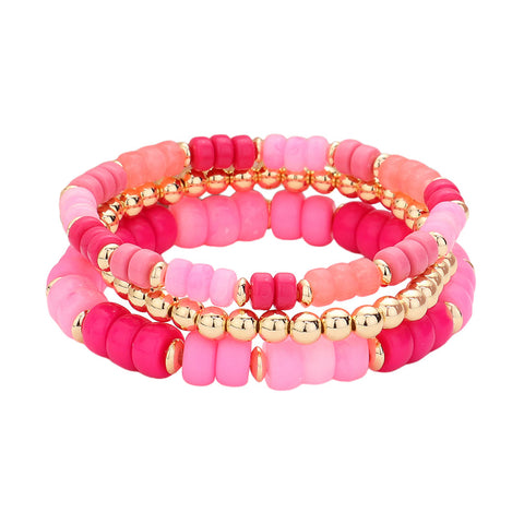 An image of three bracelets stacked on each other with two pink and one gold beaded bracelets