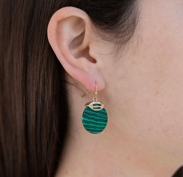 Model wearing a malachite disc earring in a gold setting.