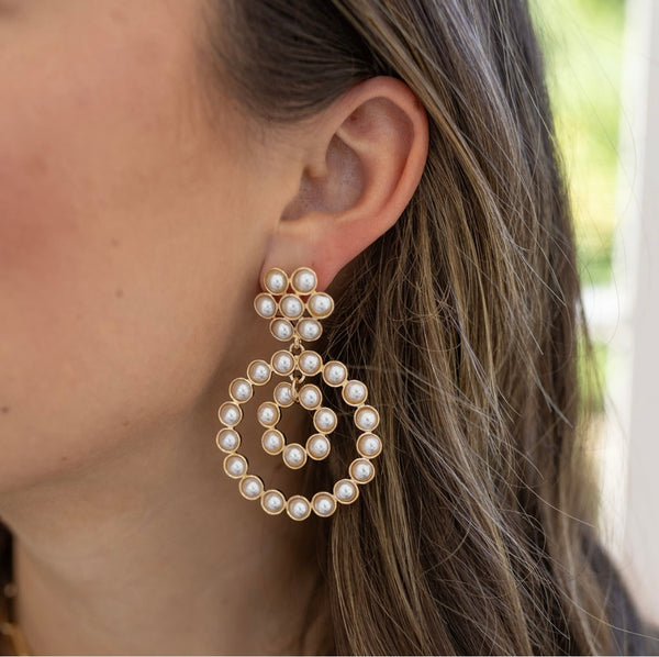 Model wearing large, dangling circular pearl earrings 