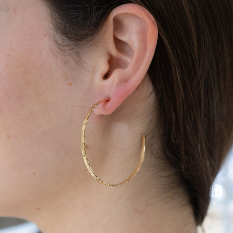 Picture of model wearing large gold hoop earrings.