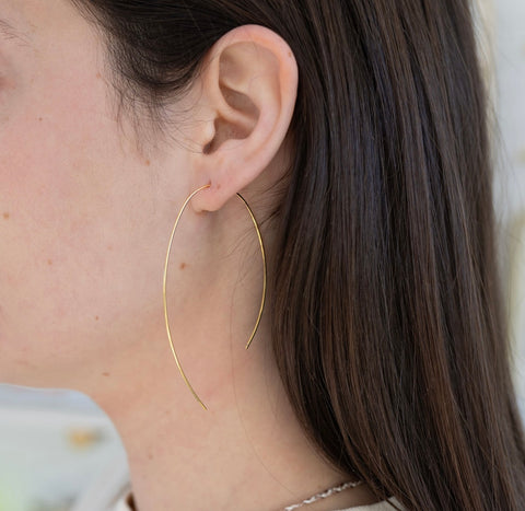 Picture of model wearing a fine gold strand earring threaded through her ear.