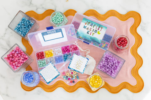 An image of a jewelry making kit with different colored beads surrounding it in jars