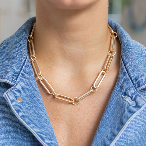 Woman wearing a thick gold paper clip chain short necklace