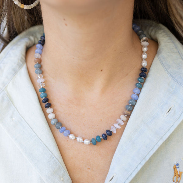 Model wearing a necklace made of varying shades of blues and white beads