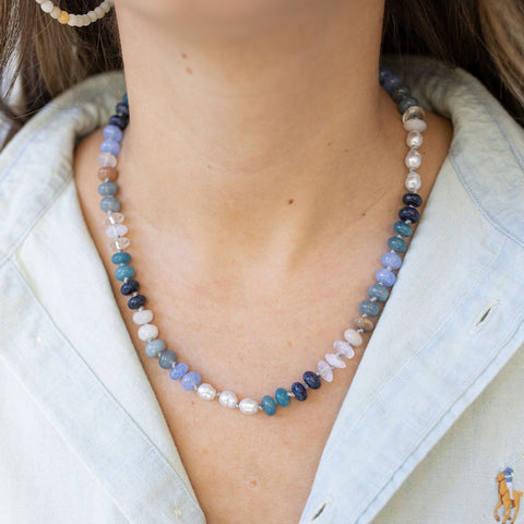 Model wearing a necklace made of varying shades of blues and white beads