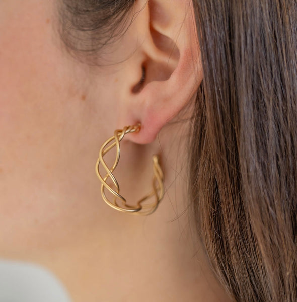 Picture of model wearing a gold hoops made of three strands of gold lightly woven together.