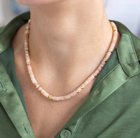 Woman wearing a short necklace with cream colored resin beads and gold spacer beads