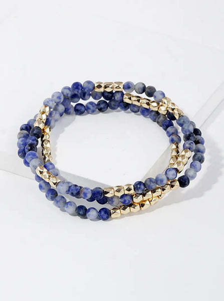 Set of three dark blue marbled beaded bracelets with gold accent beads.