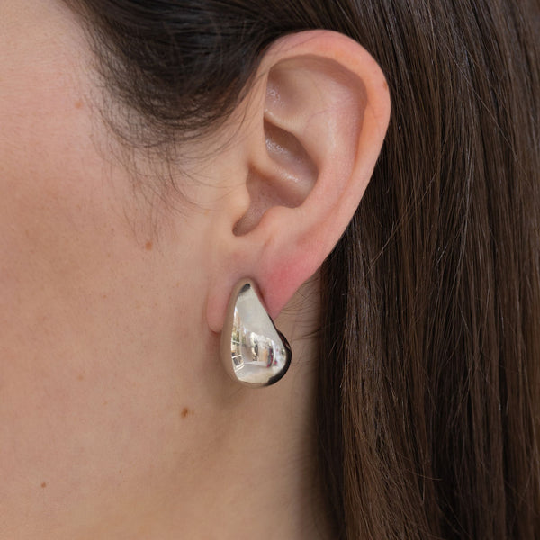 Picture of model wearing a chunky silver teardrop earring. 