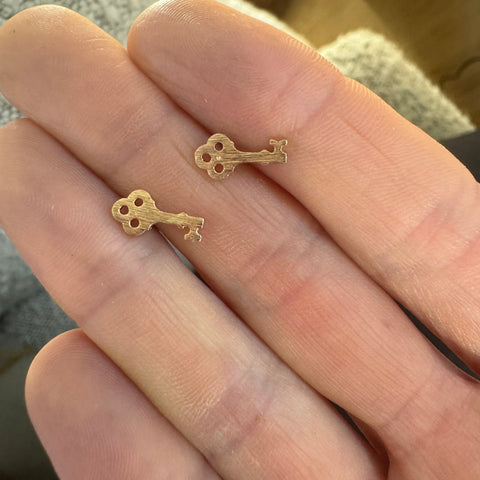 Picture of tiny gold key studs.