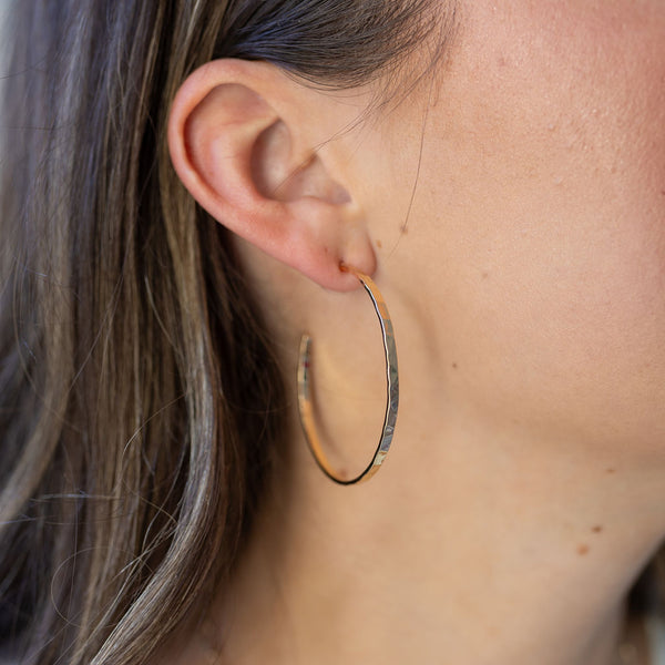 Model wearing large gold hoop earring.