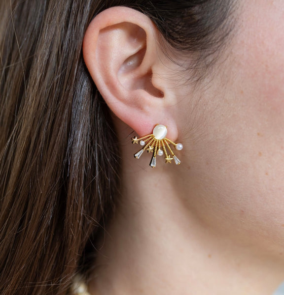 Picture of model wearing a white catseye and gold sunburst earring with gold stars, pearls and small diamonds at the tips.