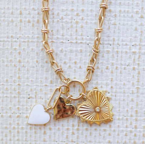 Picture of gold toggle chain with a large gold heart pendant, a white heart charm and a hammered gold heart charm.