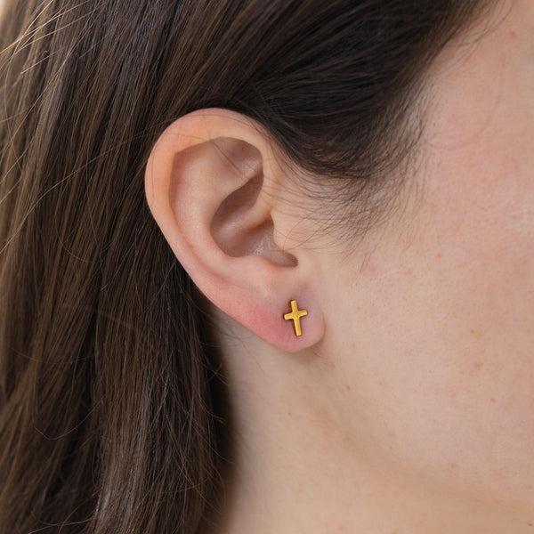 Picture of model wearing a tiny gold cross stud earrings.