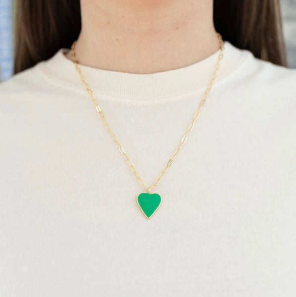 Picture of model wearing a long gold chain with a green heart pendant.