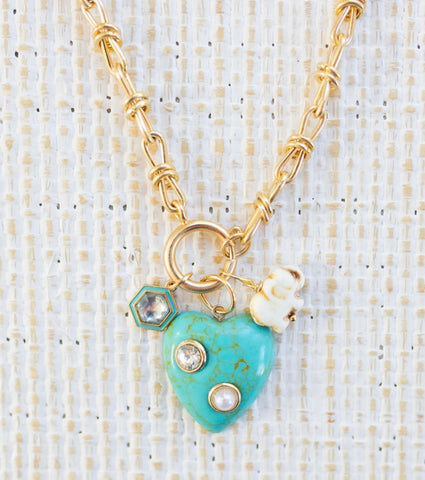 Picture of gold toggle chain with a large turquoise heart with diamond and pearl inlays. Necklace has a white elephant charm and a diamond with turquoise border charm.