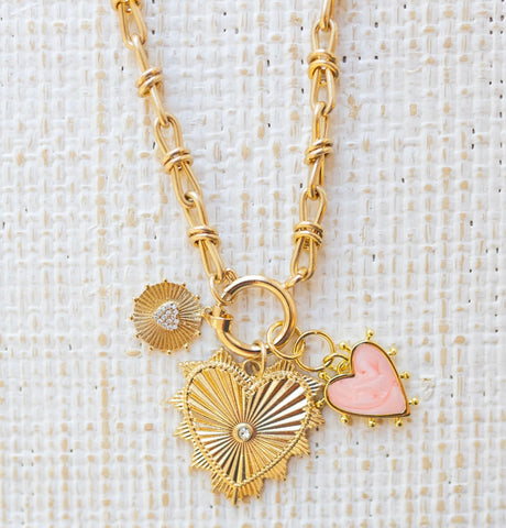 Picture of gold toggle chain with a pink heart charm, a textured gold charm with diamond heart and a large gold heart pendant with a diamond in the center.