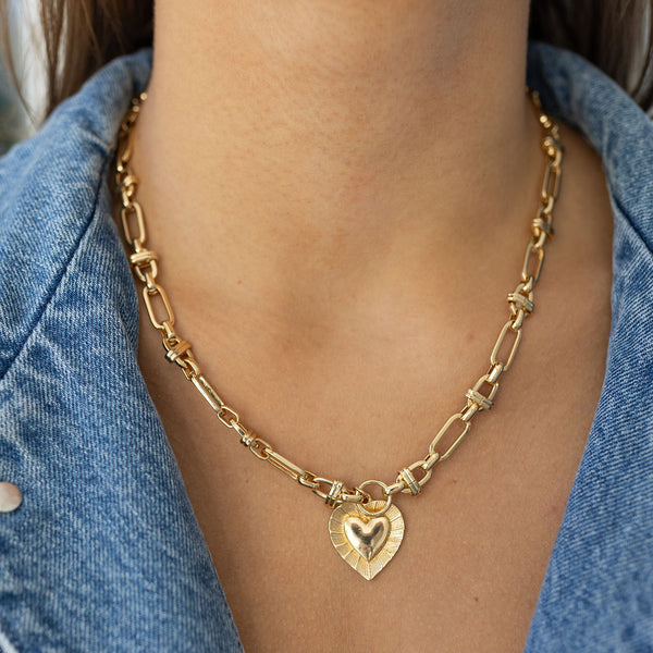 Model wearing front clasping gold toggle chain necklace with heart pendant