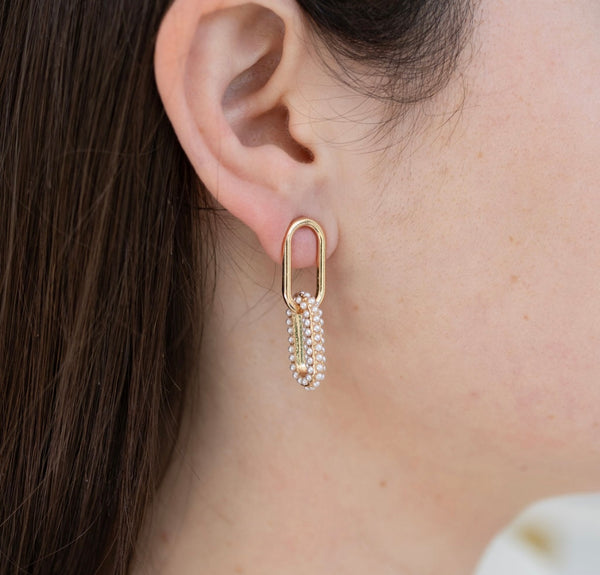 Picture of model wearing gold chain link earrings with the bottom link encrusted in pearls.