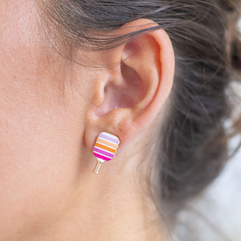 Woman wearing an orange/pink pickle ball paddle earring