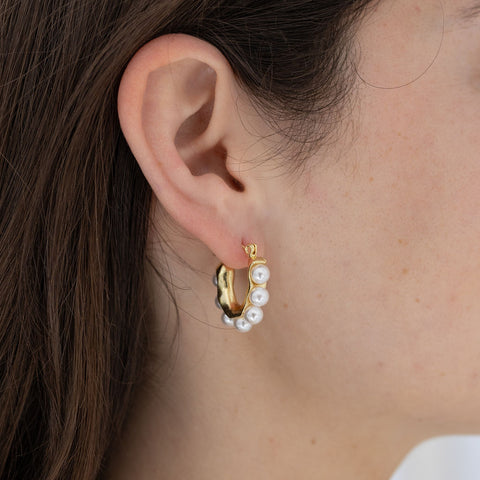 Picture of model wearing a U-shaped gold earrings inlaid with pearls.