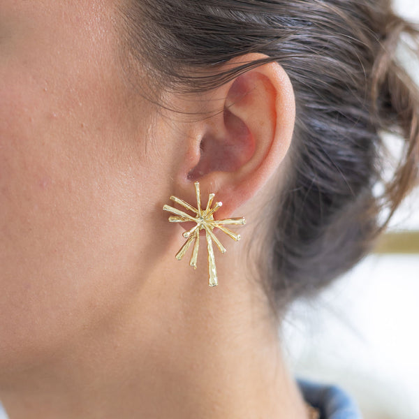 Woman wearing spikey gold stud earrings 