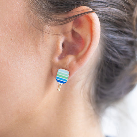 Woman wearing a blue/green pickle ball paddle earring