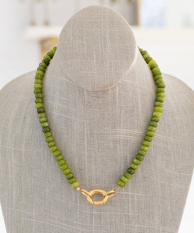 Green beaded necklace with a gold clasp in front.