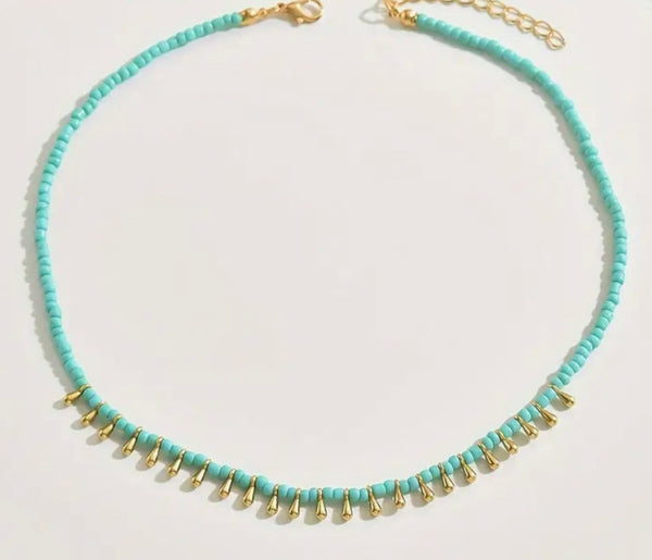 Picture of small turquoise bead necklace with tiny gold dangling accent beads at the front.