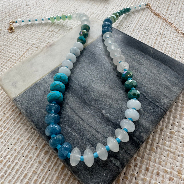 Picture of large resin bead necklace in varying shades of blue and opaque white.