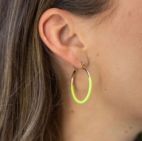 Model wearing gold hoop earring with neon yellow wrapping