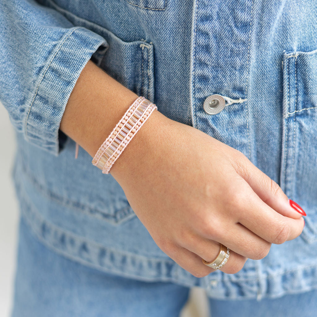 Woman wearing a beige/clear cloth beaded bracelet on her wrist