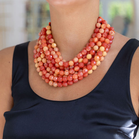 Woman wearing a layered beaded resin statement necklace with mix of red, orange, and yellow