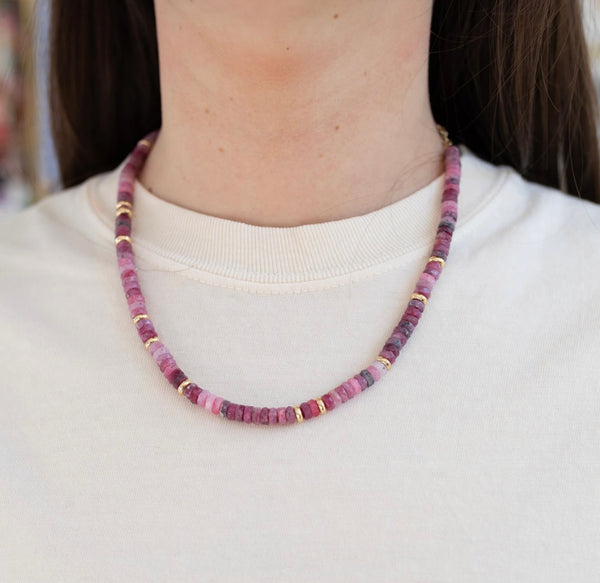 Picture of model wearing a beaded necklace made of different shades of pink with accent gold beads interspersed.