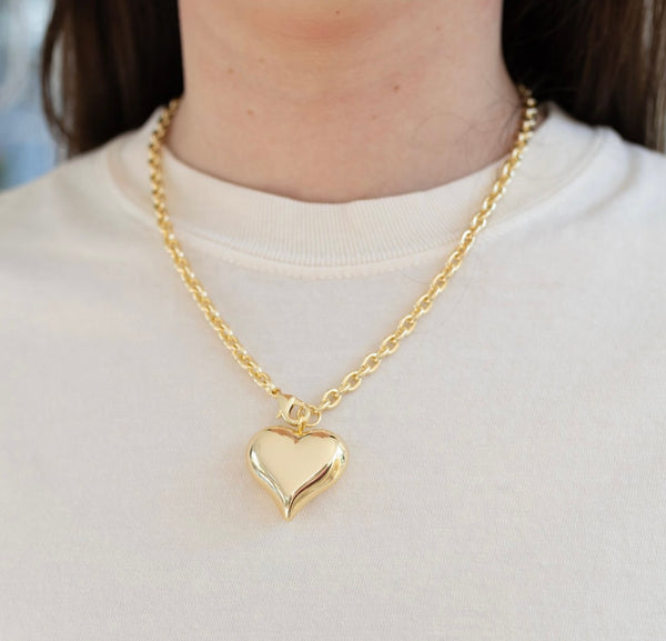 Picture of model wearing a gold chain with a large gold bubble heart pendant.