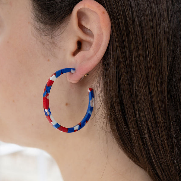 Picture of model wearing a red, white and blue resin hoop earring.