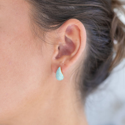 Woman wearing light blue teardrop earring studs